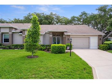 Charming single-story home featuring a well-maintained lawn, mature trees, and a cozy, inviting facade at 7445 Nature Walk Dr, Spring Hill, FL 34606