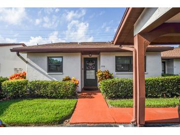 Charming single-story home with a well-manicured lawn and colorful walkway leading to the front door at 7715 Radcliffe Cir, Port Richey, FL 34668