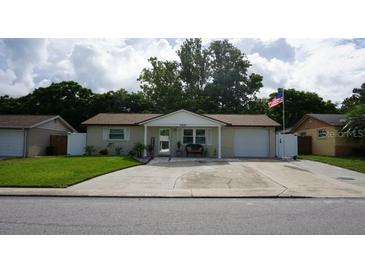 Charming single-story home featuring a well-manicured lawn, a long driveway and a cozy front porch at 11810 Oceanside Dr, Port Richey, FL 34668