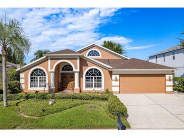 Stunning single Gathering home with a well-manicured lawn, large arched windows, and a two-car garage in a suburban neighborhood at 1831 Cardamon Dr, Trinity, FL 34655