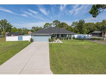Charming one-story home featuring a well-manicured lawn, concrete driveway, and stylish light blue exterior at 2027 Fentress Ct, Spring Hill, FL 34609