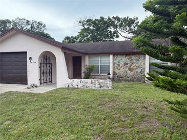 Modest single-story home featuring a stone accent wall and an arched entry at 8516 Inwood Dr, Hudson, FL 34667