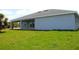 Spacious backyard view of the covered patio, sliding glass doors, and lush green lawn at 310 Day Break Cir, Port Charlotte, FL 33954