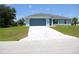 Charming one-story home featuring a blue garage door, light blue exterior, and decorative white-tiled driveway at 310 Day Break Cir, Port Charlotte, FL 33954