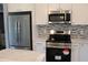 Modern kitchen features stainless steel appliances, white cabinetry, and a stylish tile backsplash at 310 Day Break Cir, Port Charlotte, FL 33954