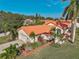 Aerial view of a home featuring lush landscaping, a red tile roof, and a well-manicured lawn at 4989 Clubview E Ct, Bradenton, FL 34203