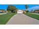 Charming single-story home featuring a long driveway, well-manicured lawn, and tropical landscaping at 4989 Clubview E Ct, Bradenton, FL 34203