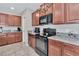 View of kitchen with wood cabinets, granite countertops and black appliances at 17009 Peaceful Valley Dr, Wimauma, FL 33598