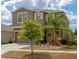 Two-story house with beige exterior, shutters, palm trees, and a well-maintained lawn at 17009 Peaceful Valley Dr, Wimauma, FL 33598