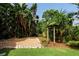 Landscaped backyard with gravel area, tropical plants, and pergola at 1713 North Dr, Sarasota, FL 34239