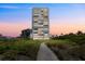 High-rise condominium building at sunset, nestled among greenery, walkway in front at 5400 Ocean Blvd # 6-4, Sarasota, FL 34242