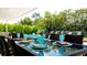 Outdoor patio dining set with blue glasses and colorful placemats, overlooking a lush garden at 676 Key Royale Drive, Holmes Beach, FL 34217