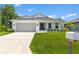 New construction home with attached garage and manicured lawn at 214 Lime Tree Park, Rotonda West, FL 33947