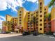 Luxury condo building with a yellow exterior, palm trees, and parking at 611 Riviera Dunes Way # 308, Palmetto, FL 34221