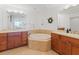 Bathroom with large soaking tub with tile surround, wooden vanity with double sinks, and tiled floors at 611 Riviera Dunes Way # 308, Palmetto, FL 34221