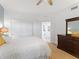 Bright bedroom with white bedding, a ceiling fan, a dark wood dresser, and an open doorway into another room at 611 Riviera Dunes Way # 308, Palmetto, FL 34221