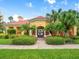 Exterior of the community clubhouse surrounded by well-maintained landscaping and bright blue skies at 611 Riviera Dunes Way # 308, Palmetto, FL 34221