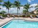 Community pool featuring a gradual entry, steel railing, and a view of the adjacent marina and palm trees at 611 Riviera Dunes Way # 308, Palmetto, FL 34221
