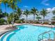 Community pool featuring a gradual entry, steel railing, and a row of palm trees lining the outer fence at 611 Riviera Dunes Way # 308, Palmetto, FL 34221