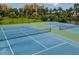 View of well-maintained community tennis courts next to a pond and grassy area with palm trees at 611 Riviera Dunes Way # 308, Palmetto, FL 34221