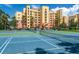 Well-maintained community tennis courts next to a modern multi-story residential building with palm trees at 611 Riviera Dunes Way # 308, Palmetto, FL 34221