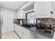 Kitchen with a black sink and dark granite countertops with white cabinets and mosaic backsplash at 301 Lambert St, Port Charlotte, FL 33948