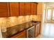 Wet bar with granite countertop, wine cooler, and wood cabinetry at 326 Saint George Ct # 14, Venice, FL 34293
