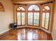 Bright bedroom featuring hardwood floors and arched windows with plantation shutters at 326 Saint George Ct # 14, Venice, FL 34293