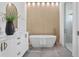 Modern bathroom featuring a freestanding tub, wood-look accent wall, and double vanity with bronze fixtures at 2111 Hawthorne St, Sarasota, FL 34239