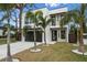 Contemporary two-story home featuring a sleek white exterior, black framed windows, and manicured lawn with palm trees at 2111 Hawthorne St, Sarasota, FL 34239