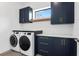 Modern laundry room with front load washer/dryer, navy cabinets, and light countertops at 2111 Hawthorne St, Sarasota, FL 34239