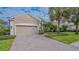 Tan two-car garage home with a paver driveway and manicured landscaping at 12327 Thornhill Ct, Lakewood Ranch, FL 34202