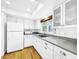 White kitchen with granite countertops, stainless steel appliances, and wood floors at 107 Los Cedros Dr, Anna Maria, FL 34216