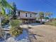 Elevated home with a spacious gravel driveway, offering a charming curb appeal at 107 Los Cedros Dr, Anna Maria, FL 34216