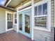 Home's exterior with teal double doors and windows leading to a deck at 107 Los Cedros Dr, Anna Maria, FL 34216