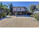 Charming elevated beach house with a gravel driveway and tropical landscaping at 107 Los Cedros Dr, Anna Maria, FL 34216