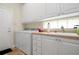 Laundry room with white cabinets and a utility sink at 5814 Benevento Dr, Sarasota, FL 34238