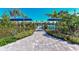 Club Belize community pool area with a paved pathway, lush landscaping, and shaded seating at 27460 Janzen Ct, Englewood, FL 34223