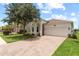 White house with arched entryway, paver driveway, and mature landscaping at 18901 Muhly Grass Ln, Lutz, FL 33558