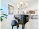 Elegant dining room featuring a grand piano and chandelier with views into the kitchen at 8678 Rain Song Rd, Sarasota, FL 34238