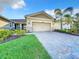 Charming home featuring a two-car garage, paver driveway, stone accents, and well-manicured landscaping at 8678 Rain Song Rd, Sarasota, FL 34238