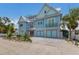 Charming two-story home with light teal exterior, paver driveway, and tropical landscaping at 118 Mangrove Ave, Anna Maria, FL 34216
