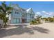 Two-story teal home with paver driveway, landscaping, and gated entrance at 118 Mangrove Ave, Anna Maria, FL 34216