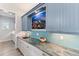 Butler's pantry with granite countertop, blue cabinets, and a mosaic backsplash at 118 Mangrove Ave, Anna Maria, FL 34216