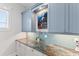 Butler's pantry with granite countertop, blue cabinets, and a mosaic backsplash at 118 Mangrove Ave, Anna Maria, FL 34216