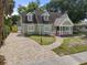 Charming green home featuring a welcoming front porch, brick driveway, and well-maintained landscaping at 7754 Westmoreland Dr, Sarasota, FL 34243