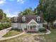 Inviting green home with classic dormers, a cozy front porch, and a neatly landscaped yard at 7754 Westmoreland Dr, Sarasota, FL 34243