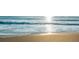Sparkling ocean waves gently meet the golden sand, creating a serene beach scene bathed in sunlight at 757 Hideaway Bay Dr, Longboat Key, FL 34228