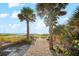 Picturesque beach access path with benches, framed by palm trees and serene beach views at 757 Hideaway Bay Dr, Longboat Key, FL 34228