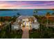 Beautiful waterfront home with lush landscaping, brick driveway, and a serene bay view at sunset at 757 Hideaway Bay Dr, Longboat Key, FL 34228